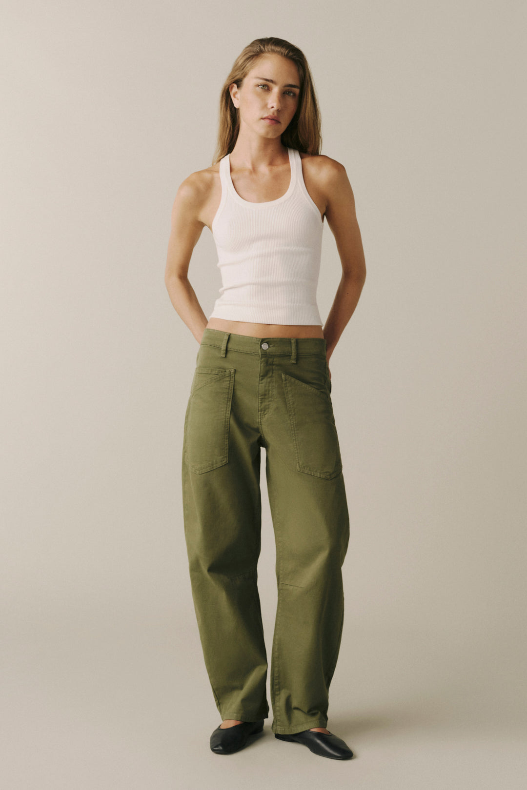 A woman modeling a pair of olive green wide-leg cargo pants with a white ribbed tank top.