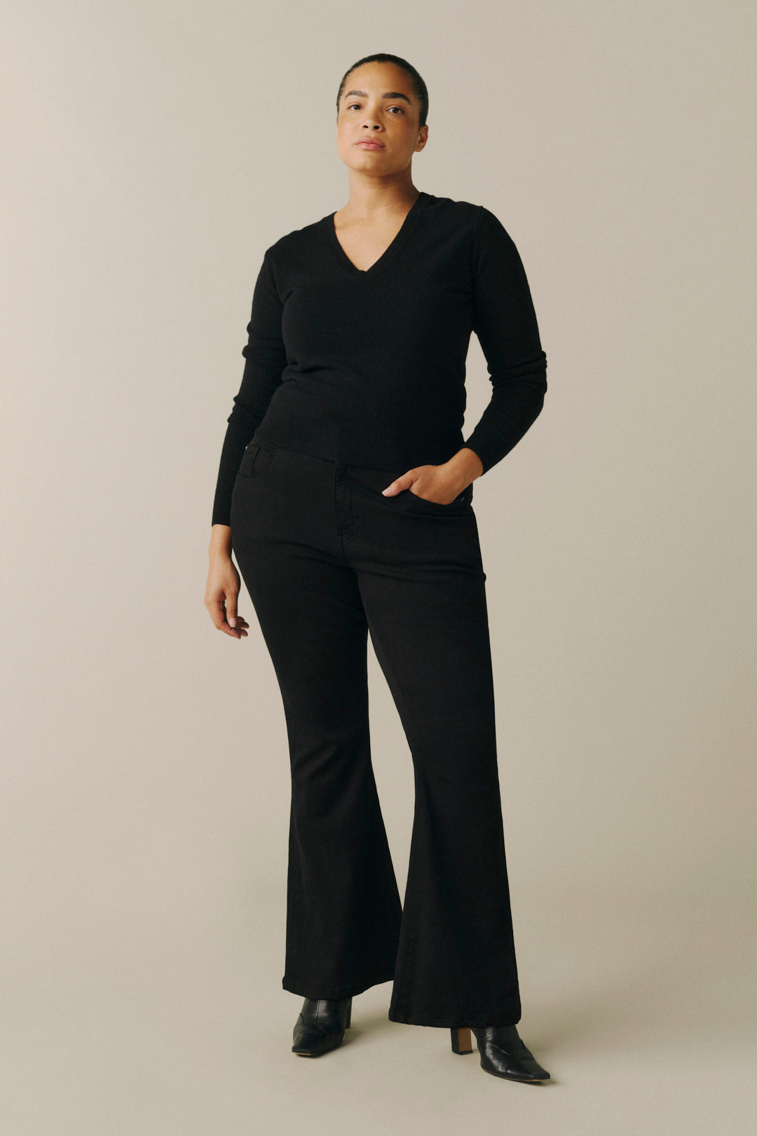 A woman modeling a black long-sleeve V-neck top and matching black wide-leg pants.