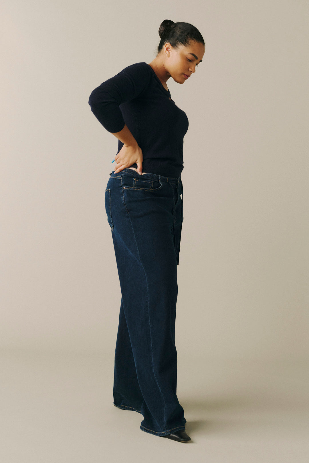 A woman modeling a pair of dark blue wide-leg jeans with a dark navy long-sleeve top.
